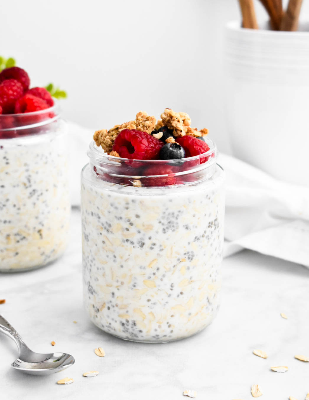 A jar of overnight oats topped with raspberries, blueberries, and granola.