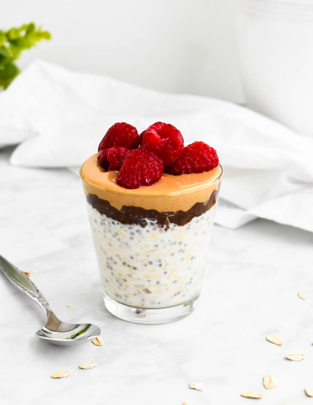 Overnight oats topped with a tablespoon each of peanut butter and jam and topped with raspberries.