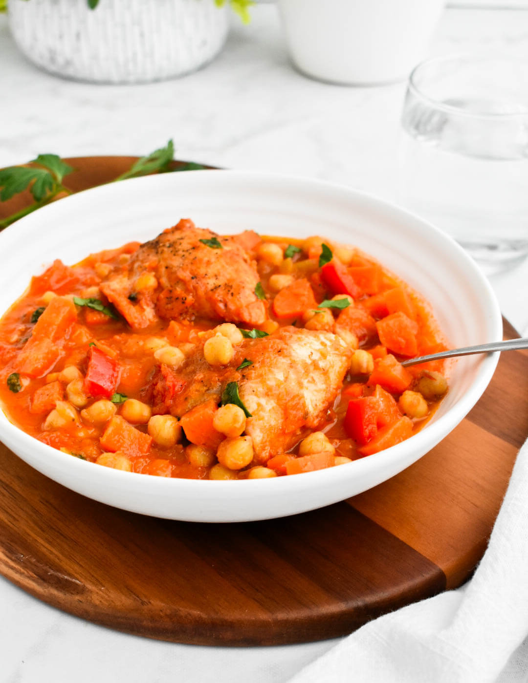 A bowl of Greek chicken and chickpea stew topped with two chicken thighs.