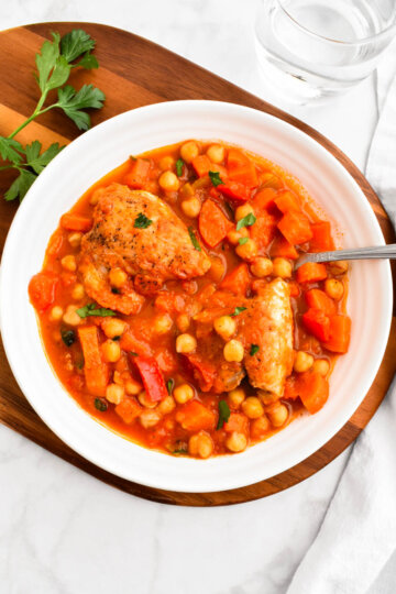 A bowl of Greek chicken and chickpea stew sprinkled with parsley.