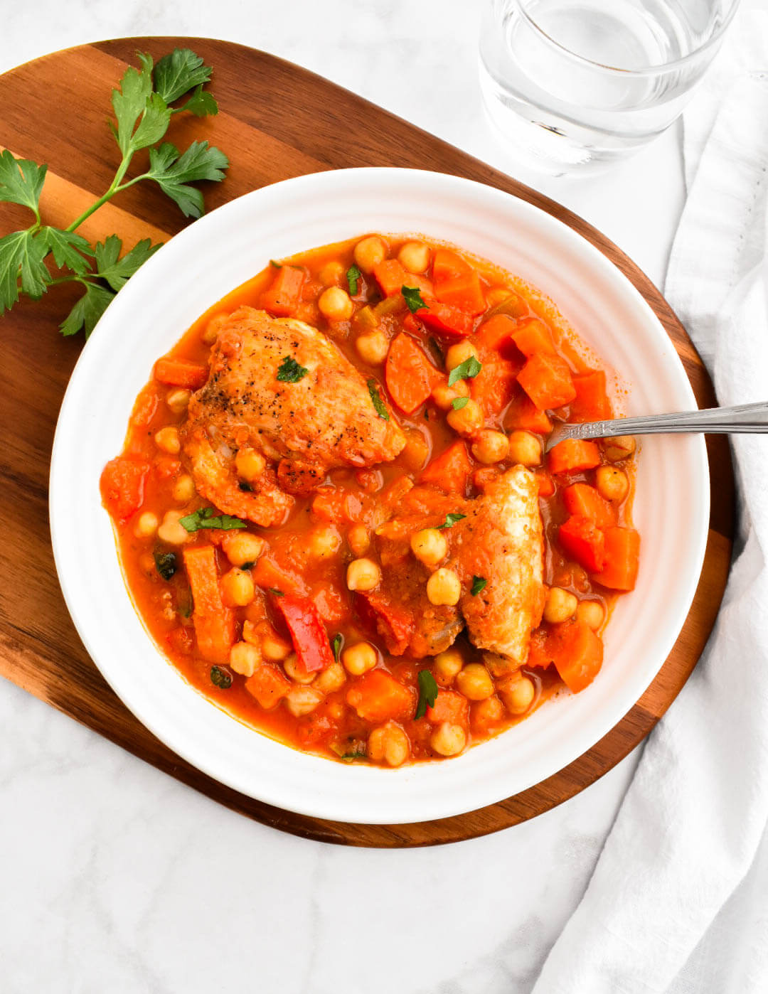 A bowl of Greek chicken and chickpea stew sprinkled with parsley.